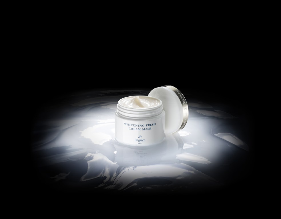 Whitening cream mask product shot. Cosmetic container and lid product photo featuring white and gray colors against a black background.