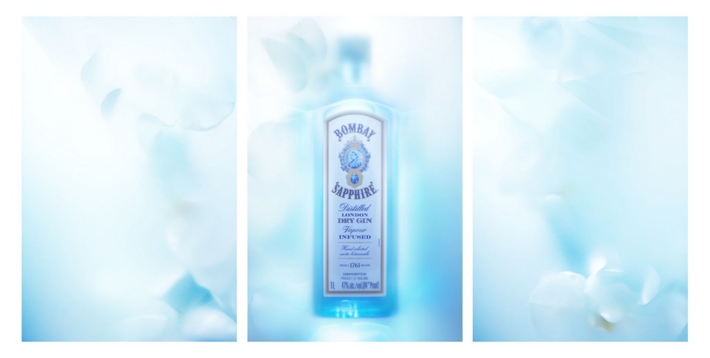 Bombay Sapphire gin bottle product shot with a white label, set against an out-of-focus ethereal light blue floral background.