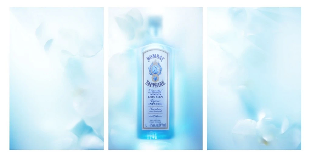 Bombay Sapphire gin bottle product shot with a white label, set against an out-of-focus ethereal light blue floral background.