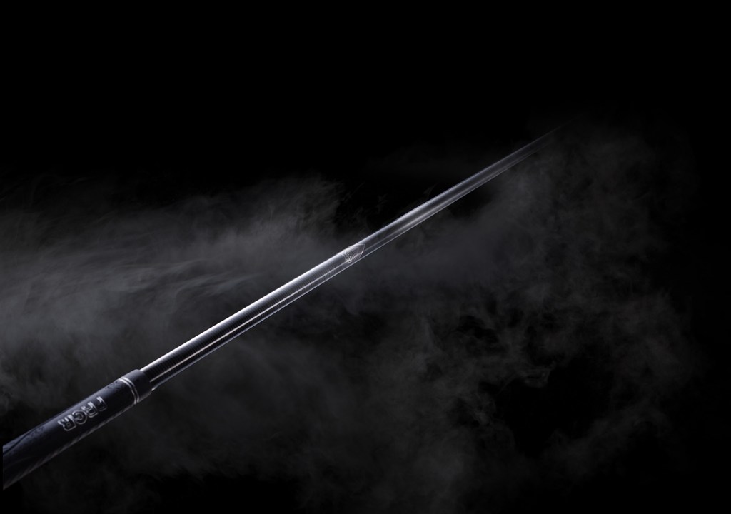 Angled golf club shaft in studio with atmospheric smoke against black backdrop, close-up shot showcasing sports equipment.