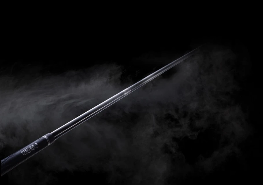 Angled golf club shaft in studio with atmospheric smoke against black backdrop, close-up shot showcasing sports equipment.