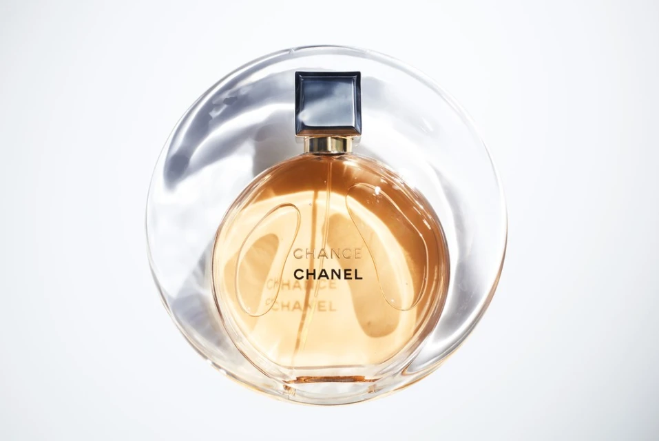 Still life studio shot of a Chanel Chance perfume bottle with a transparent plastic disk creating a light, minimalist beauty product image.