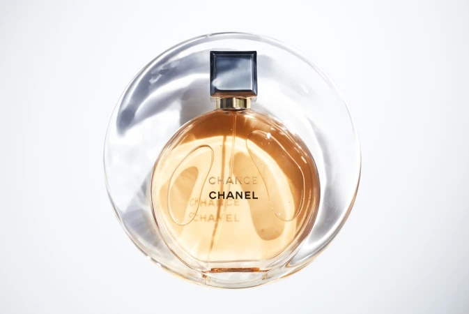 Still life studio shot of a Chanel Chance perfume bottle with a transparent plastic disk creating a light, minimalist beauty product image.