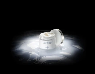 Open white cosmetic cream jar resting on a reflective liquid surface against a dark background