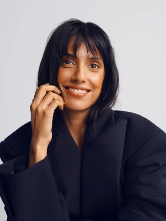 Portrait of smiling woman in black blazer against white background photographed by Rosaline Shahnavaz