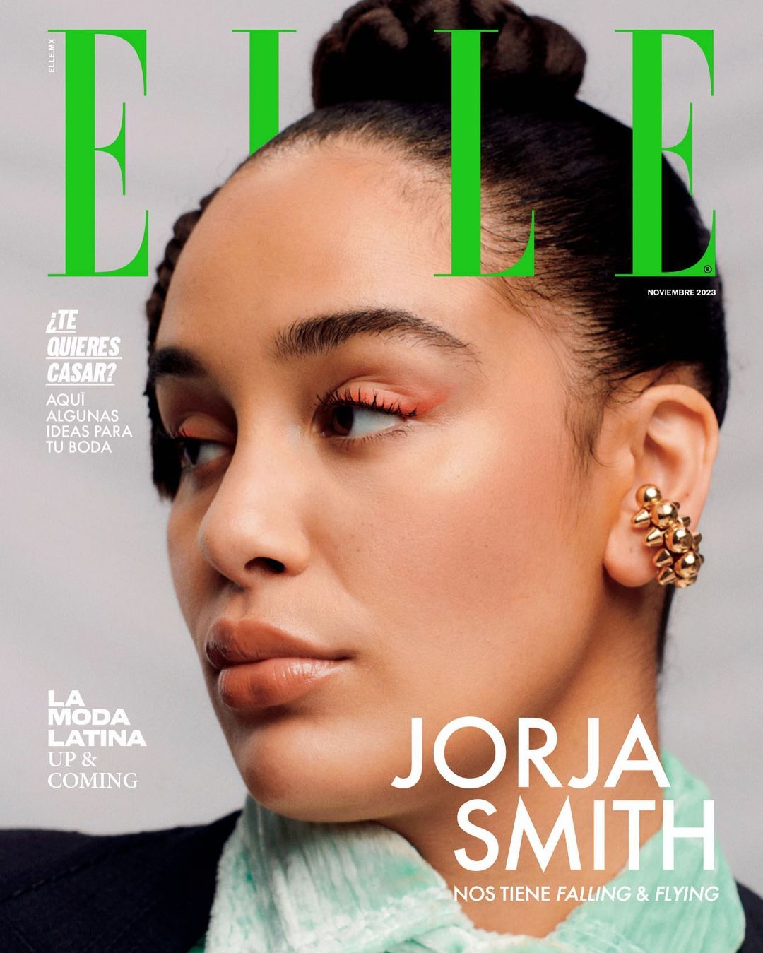 Portrait of Jorja Smith wearing a textured pale green scarf and a gold ear cuff against a light grey background.