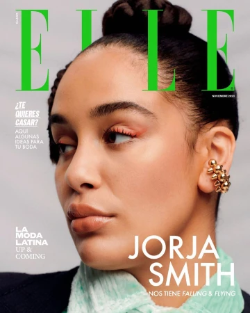 Portrait of Jorja Smith wearing a textured pale green scarf and a gold ear cuff against a light grey background.