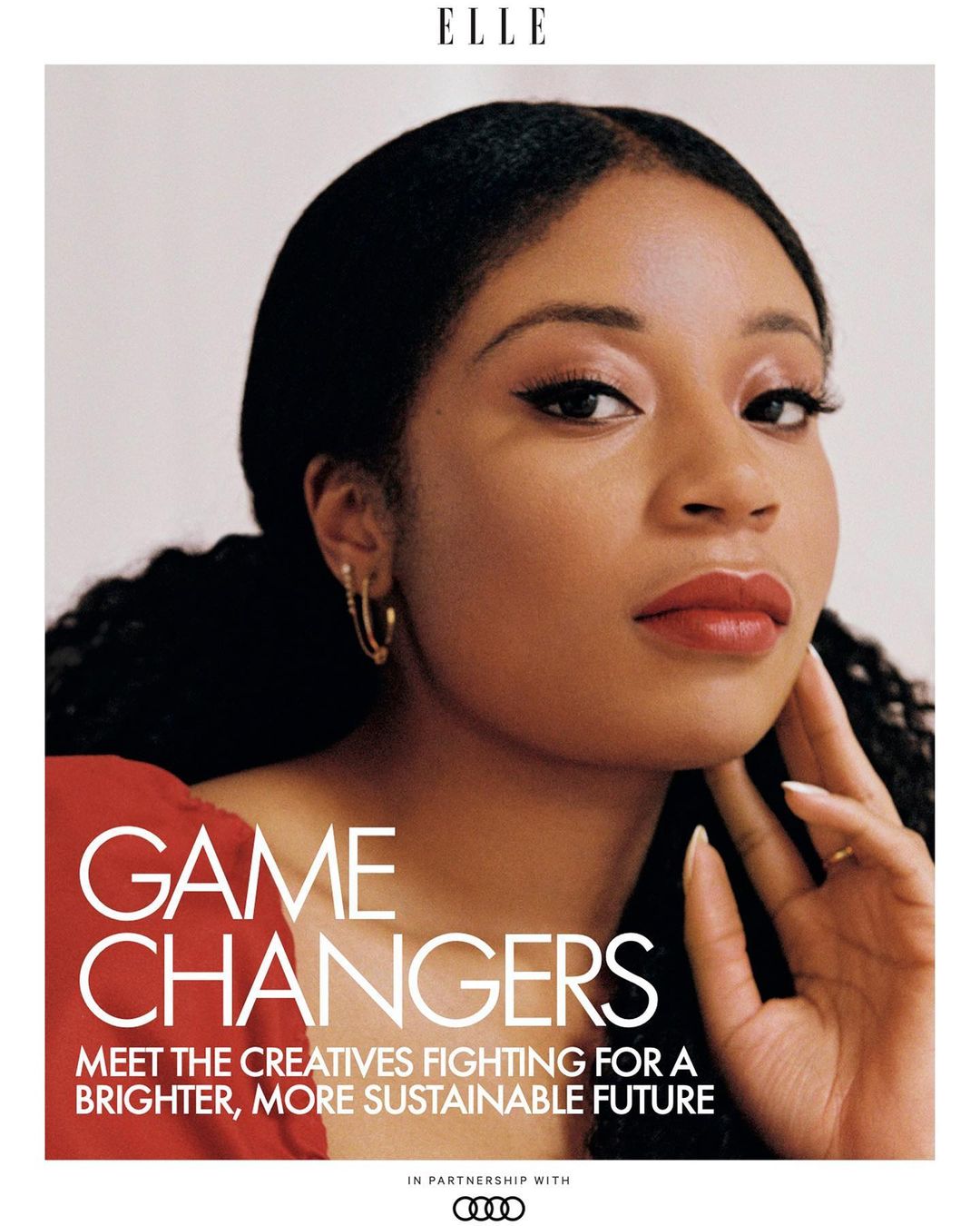 Close-up portrait of a Black woman with curly hair, wearing red top and gold earrings, against a light background, Elle magazine cover.