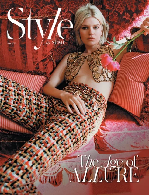 Magazine cover featuring a woman in an ornate outfit reclining on a red patterned sofa, holding a pink flower, with 'Style' in bold text.