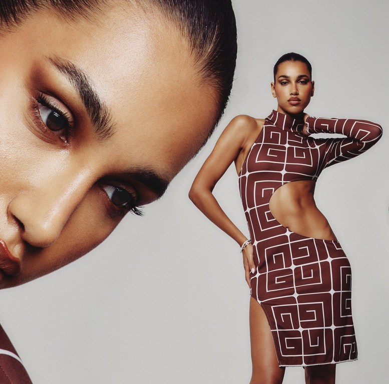 Fashion shot of a woman posing in a brown and white geometrically patterned dress against a grey background with soft lighting.