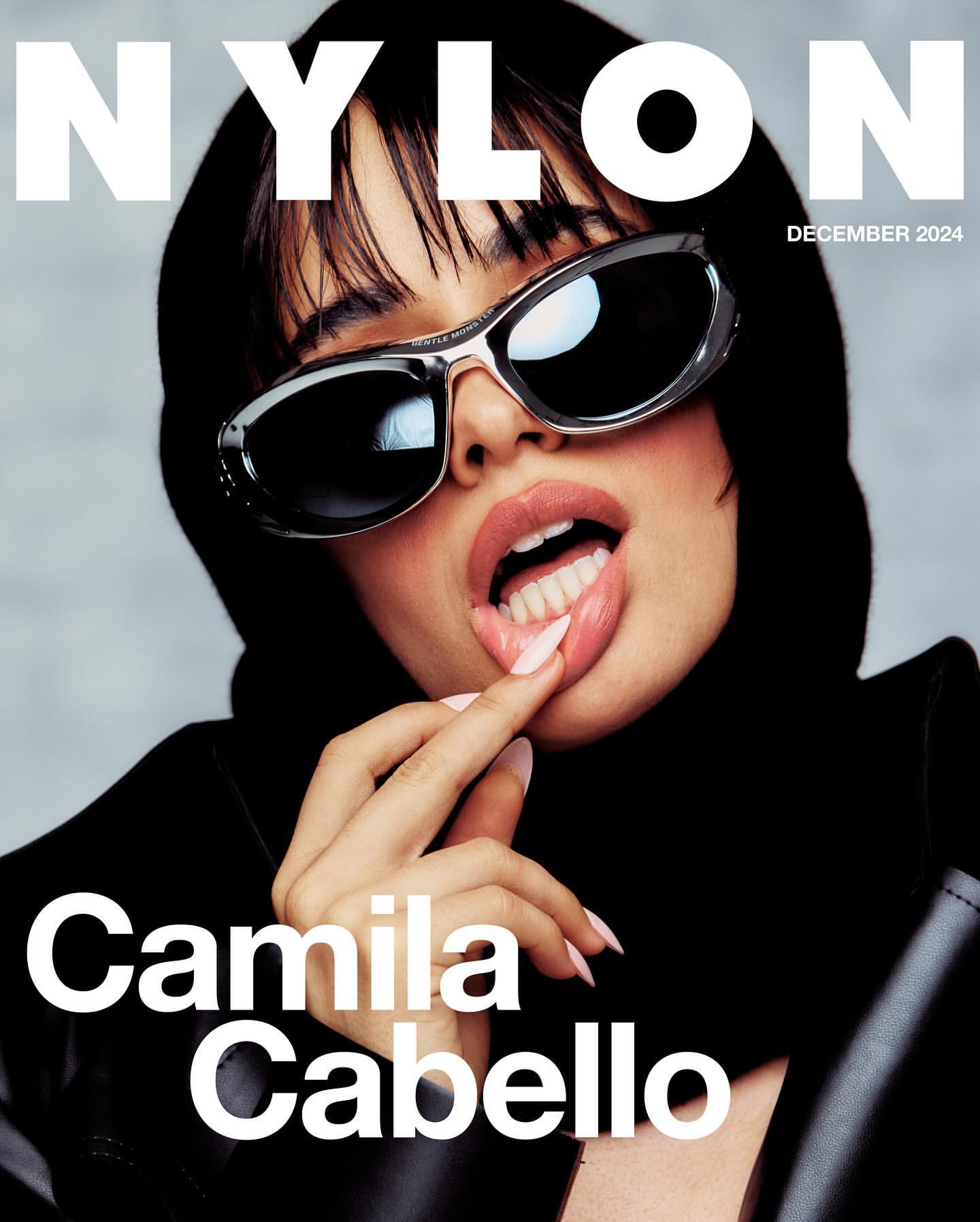 Camila Cabello on Nylon Magazine cover, December 2024 issue, wearing sunglasses and black hooded jacket, with finger touching her lips.
