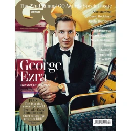 George Ezra sitting inside a red bus wearing a black suit jacket and bow tie, photographed by Tomo Brejc for British GQ.