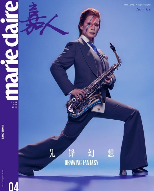 Lucy Liu on the cover of Marie Claire Taiwan April 2020, wearing a suit with a blue tie and holding a saxophone against a blue background.