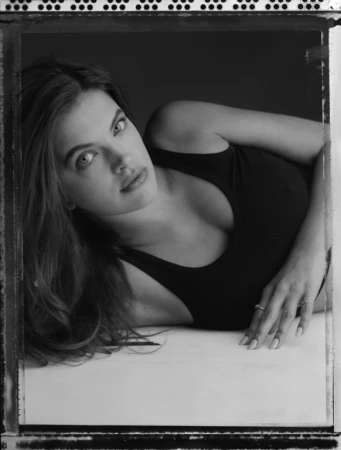 Black and white portrait of a woman in a dark tank top lying down, photographed by Victor Demarchelier