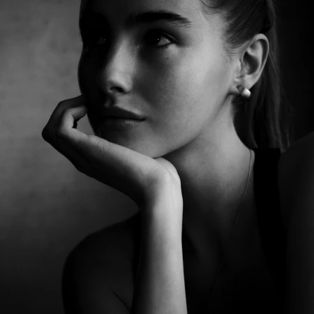 Close-up monochrome portrait of a young woman resting her chin on her hand, captured by Victor Demarchelier.