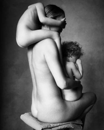 Monochrome portrait of a seated woman holding two young children by photographer Victor Demarchelier