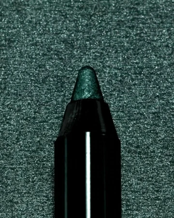 Close-up of a dark green eyeliner pencil with a shiny tip, set against a dark glittering green background.