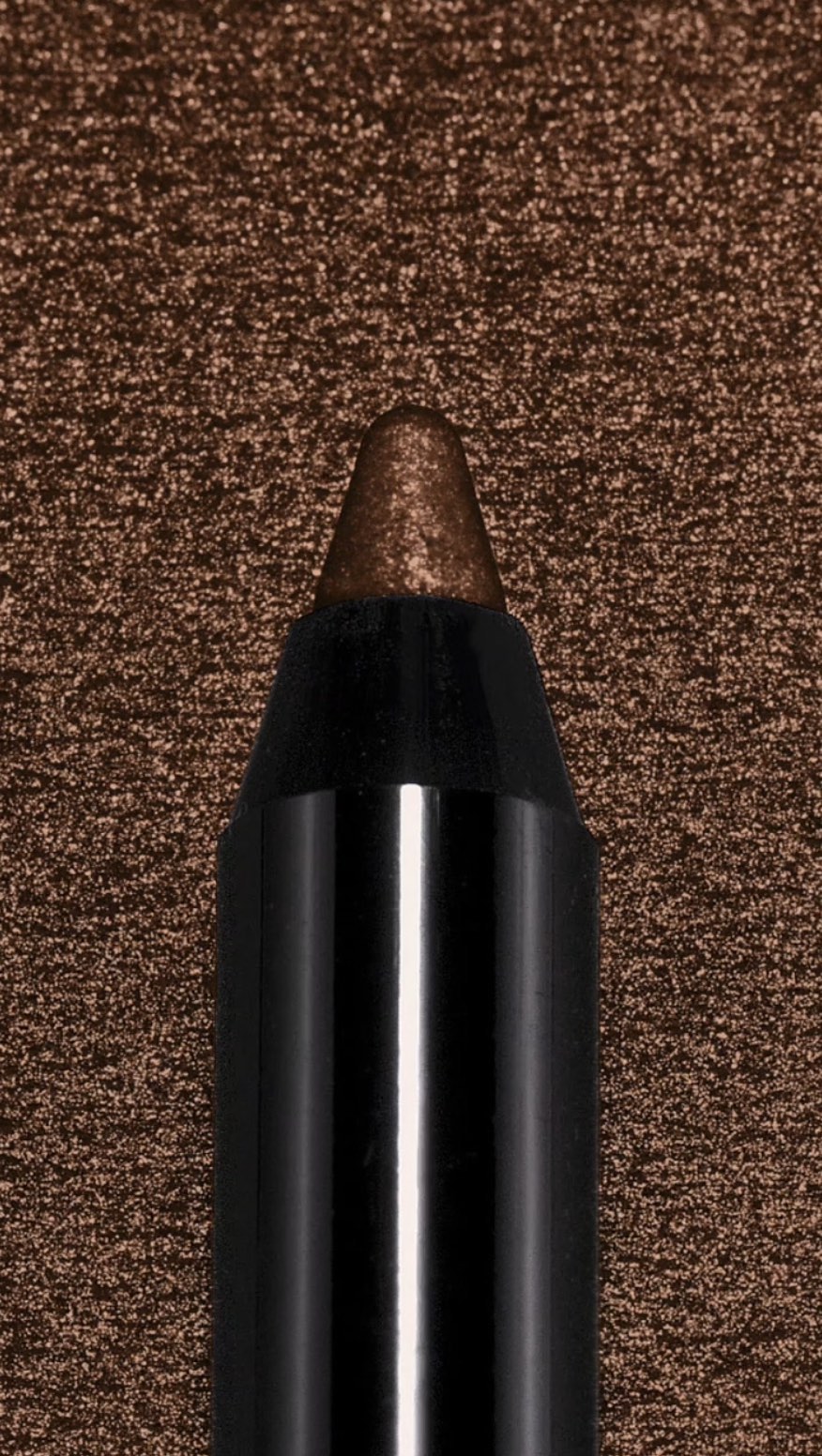 Close-up of a brown eyeliner pencil with a black casing, positioned against a textured brown background. Beauty product detail.