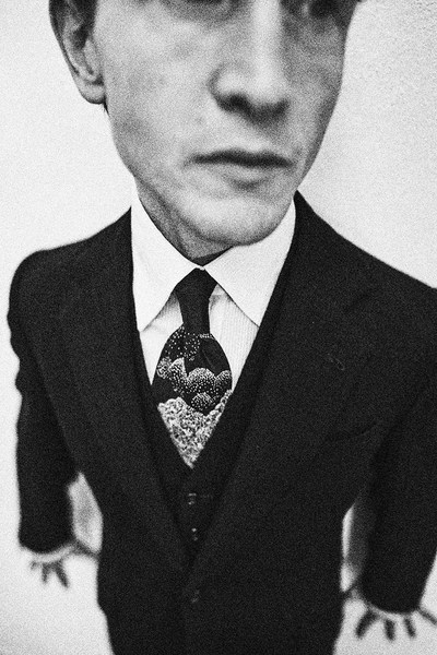 Black and white portrait of a man in a suit and tie with a wide-angle lens, close-up view, capturing his face and formal attire.