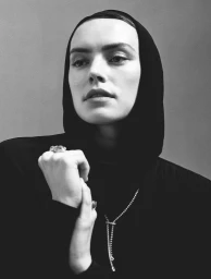 Monochrome portrait of Daisy Ridley wearing a black hooded top and statement jewellery styled by Katie Felstead