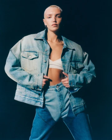 Model with a buzzcut wearing an oversized denim jacket and jeans, styled by Katie Felstead in London.