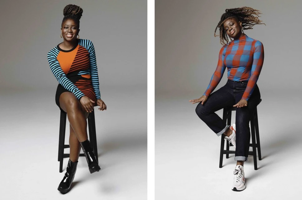 Two Black women seated on stools in a photo studio. One wears a striped dress and patent boots, the other a checkered top and jeans.