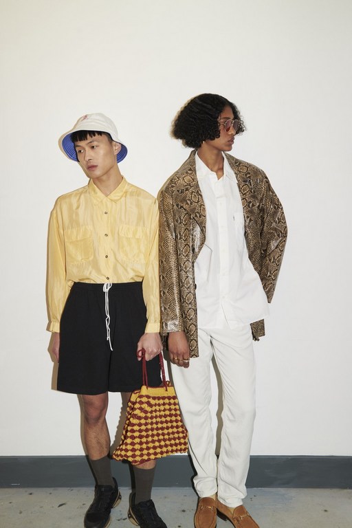 Two people pose in stylish casualwear against a plain white backdrop in a studio setting, showcasing a contemporary fashion aesthetic.