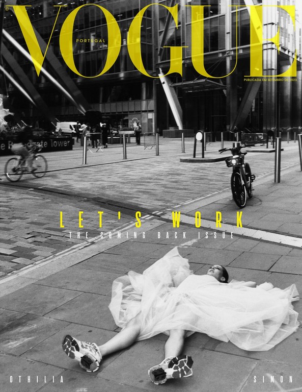 Fashion magazine cover featuring a model in a white dress lying on a city street with a modern building backdrop and bold yellow text.