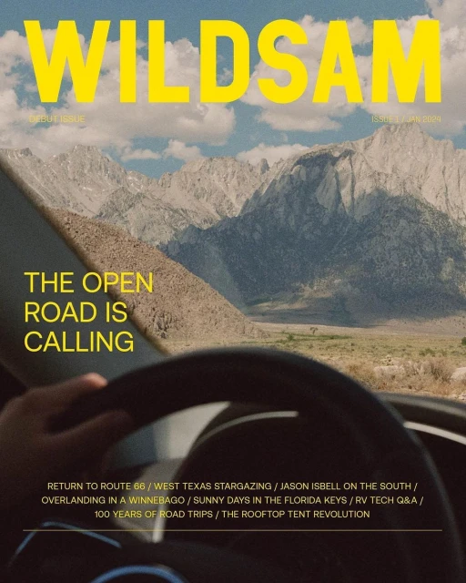 Magazine cover featuring a car dashboard view of a mountain road, titled 'WILDSAM,' blending travel and automotive themes in an outdoor setting.