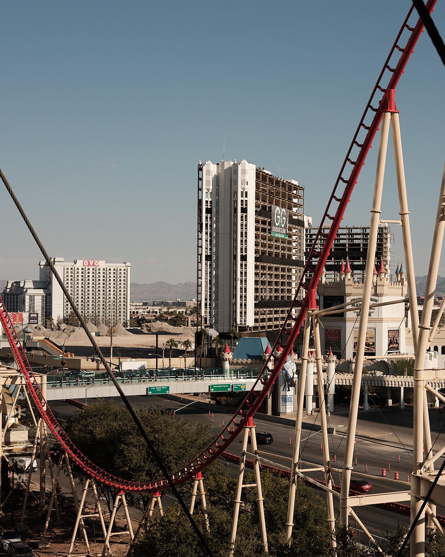 View of a roller coaster in Las Vegas, Nevada, featuring architectural buildings against a clear sky on a sunny day in an urban setting.