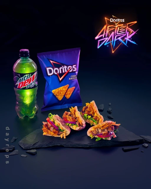 Chips and tacos served with Mountain Dew on a slate platter against a dark backdrop with neon brand logo.