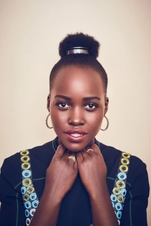 Close-up portrait of an adult Black woman with an updo hairstyle, gold hoop earrings, and a dark-colored, embroidered dress in a studio.