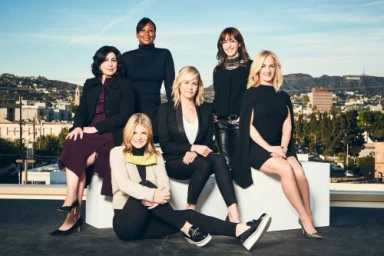 Group of six women posing on a rooftop in Los Angeles with city views and the Hollywood sign in the background.