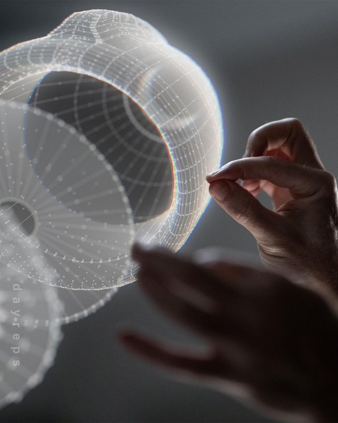 Hands interact with a semi-transparent, spherical CGI wireframe model in a grey studio setting, showcasing technology and design.