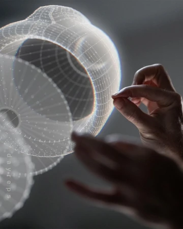 Hands interact with a semi-transparent, spherical CGI wireframe model in a grey studio setting, showcasing technology and design.