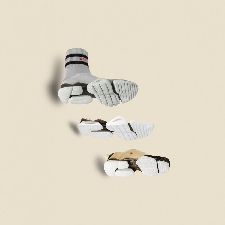 Studio shot of three Vetements sock-style sneakers with chunky, futuristic soles on a neutral background, showcasing fashion footwear.