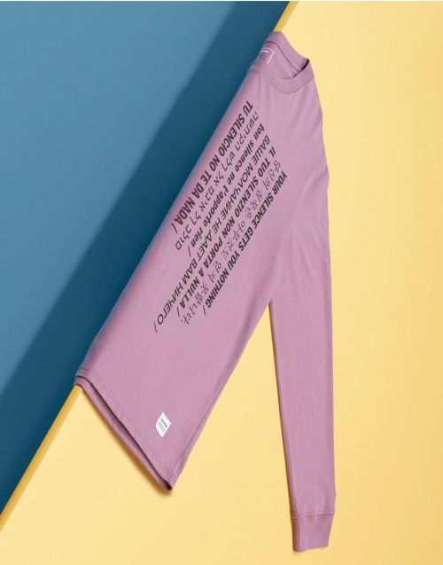 Long sleeved shirt with text in multiple languages on blue and yellow background. Top clothing apparel product flat lay.