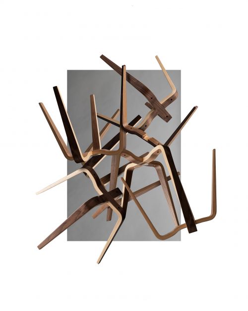 Abstract sculpture of bent light and dark wood pieces overlapping in front of a gray rectangle on a white background, studio lighting.