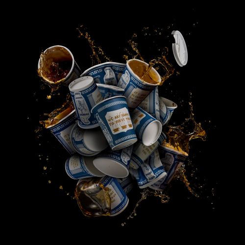 Multiple Anthora paper coffee cups with blue Greek diner design, some spilling liquid in a dynamic composition against black.