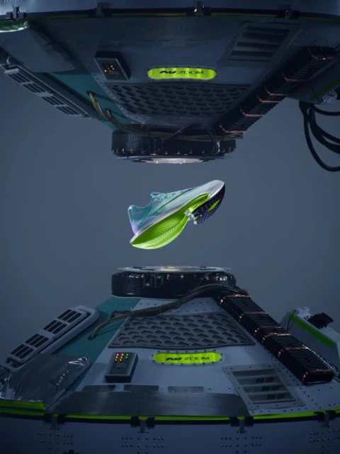 Product shot showcasing a light blue and neon green running shoe suspended between two futuristic metallic platforms with neon accents.