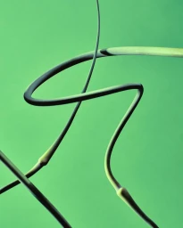 Curved and linear metallic tubes intersecting against a solid green studio backdrop
