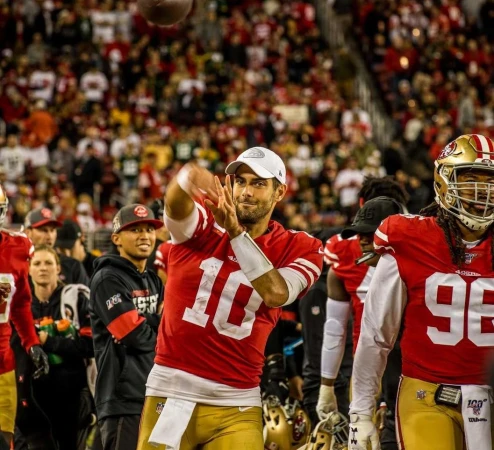 Football player throws the ball in front of a crowd of spectators at a stadium. Red and gold uniform with the number 10.