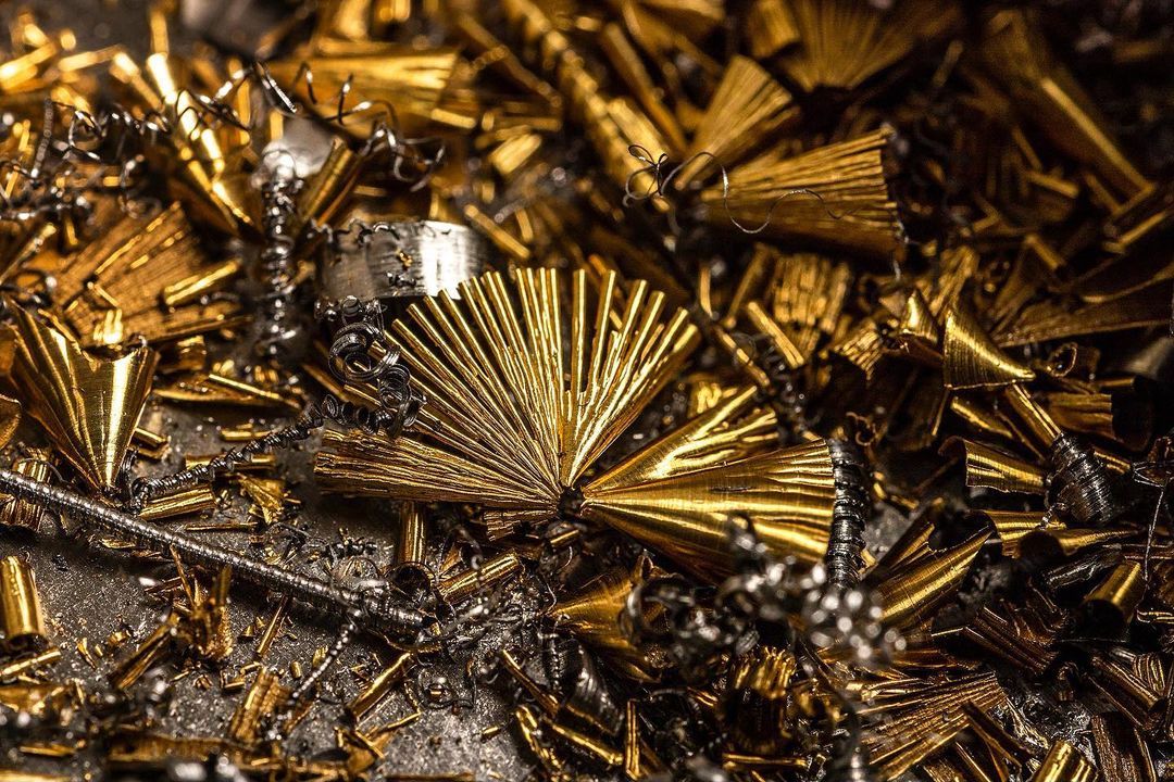 Close-up of gold and silver metal shavings and turnings scattered across a surface, showcasing intricate textures and industrial aesthetics.