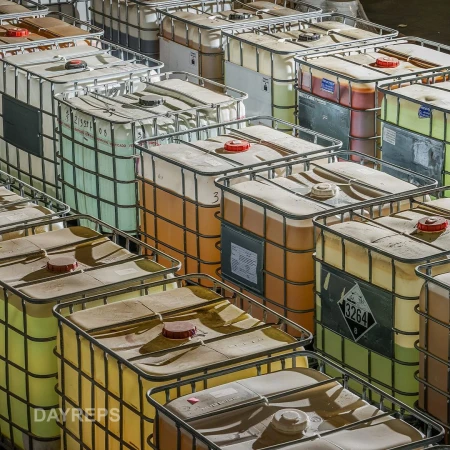 Large intermediate bulk containers (IBCs) filled with liquids are densely arranged in a warehouse, suggesting storage for industrial purposes.