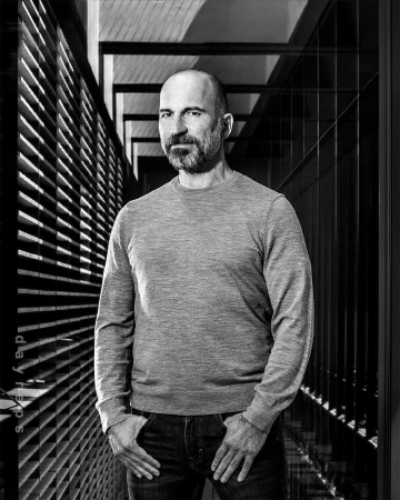 Portrait of a man with a beard wearing a grey sweater standing in a hallway by Christie Hemm Klok