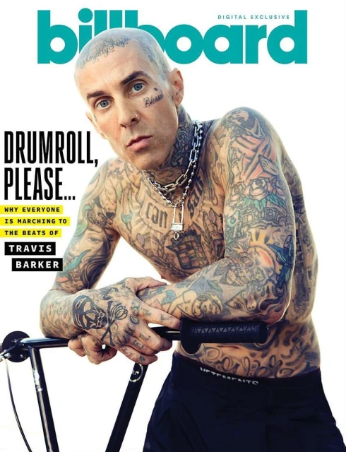 Billboard cover featuring Travis Barker, shirtless with tattoos, silver chain, and dark pants, posing indoors near a walker or mobility aid.
