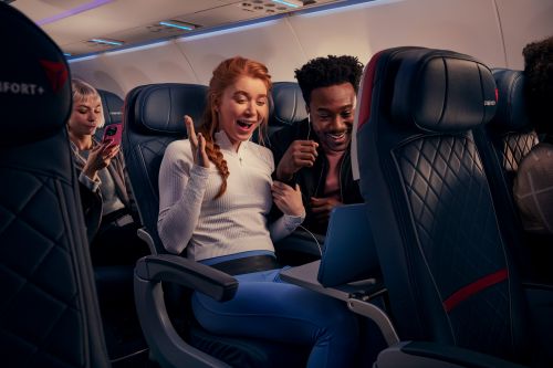 Passengers enjoy in-flight entertainment with a laptop on a Delta Comfort+ flight, showcasing modern travel with Delta's airline services.