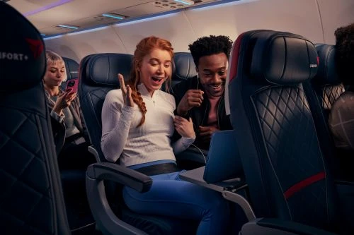Passengers enjoy in-flight entertainment with a laptop on a Delta Comfort+ flight, showcasing modern travel with Delta's airline services.