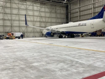 Commercial airplane inside a large industrial aircraft hangar with concrete flooring, photographed by Christopher Patey