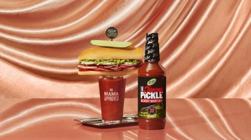 Still life of sandwich and Bloody Mary mix, featuring Jimmy's Famous Bloody Mary Pickle Mix and Mama Approved branding in a studio.